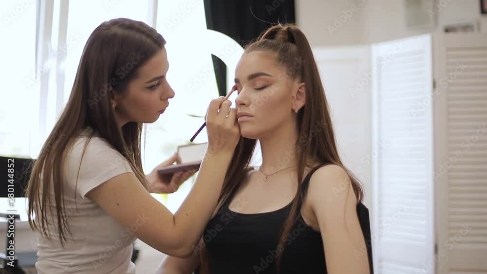 Make up artist doing professional make up of young redhead woman with freckles Make up artist doing professional make up of young redhead woman with freckles