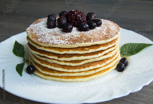 Pancake with powdered sugar, blueberries and blackberries on a plate
