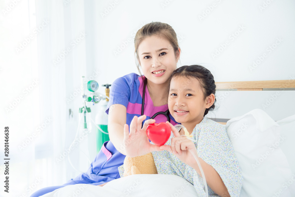 Asian girl patient and female doctor holding red heart ball and smile together Asian girl patient and female doctor holding red heart ball and smile together