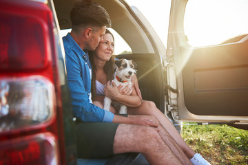 Loving couple with dog enjoying the view in summertime
