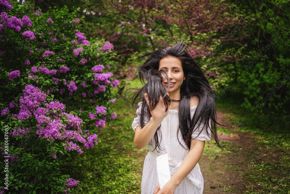 woman posing on background of blooming bush with lilac flowers . girl waving hair . space for text. woman posing on background of blooming bush with lilac flowers . girl waving hair . space for text.
