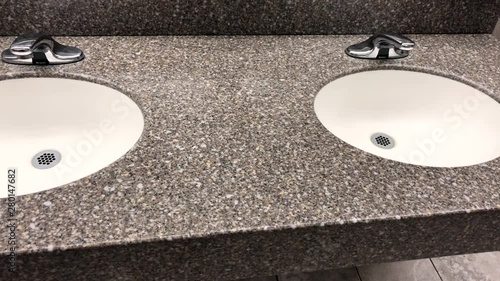 Bathroom granite countertop with two oval white under mount sinks with faucet and tiled walls and floors around photo