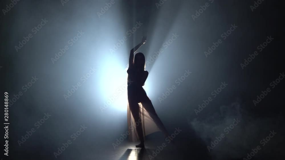 Motion of a charming female performing contemp in dark studio. Motion of a charming female performing contemp in dark studio.