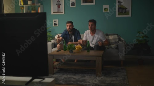 Two best friends watching sport competition on tv at home, enjoying good game