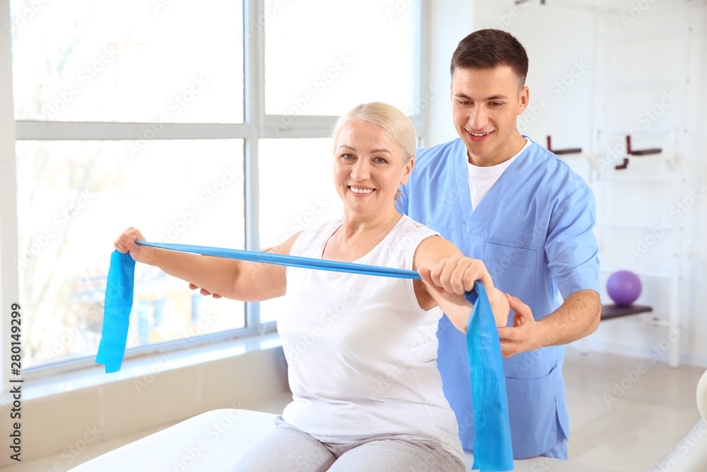 Fototapeta premium Physiotherapist working with mature patient in rehabilitation center