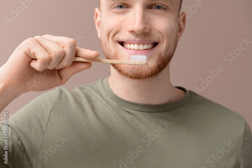 Young man cleaning teeth on...