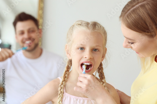 Mother teaching little girl to clean teeth at home