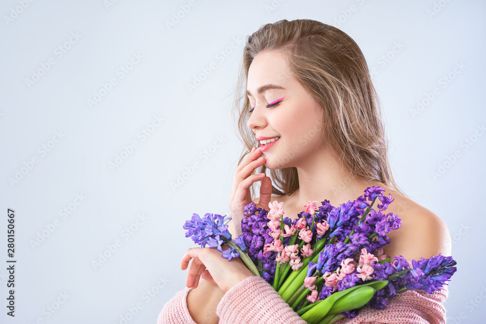 Beautiful young woman with hyacinth flowers on light background Beautiful young woman with hyacinth flowers on light background