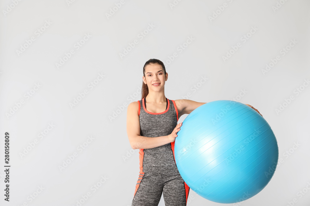Young sporty woman with fitball on grey background Young sporty woman with fitball on grey background