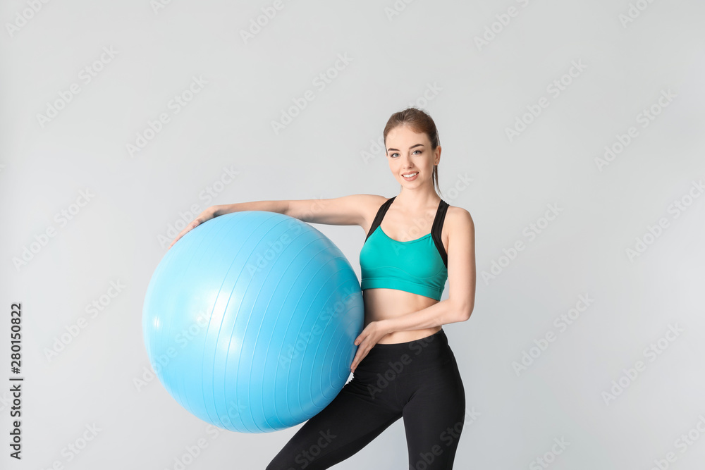 Young sporty woman with fitball on grey background Young sporty woman with fitball on grey background