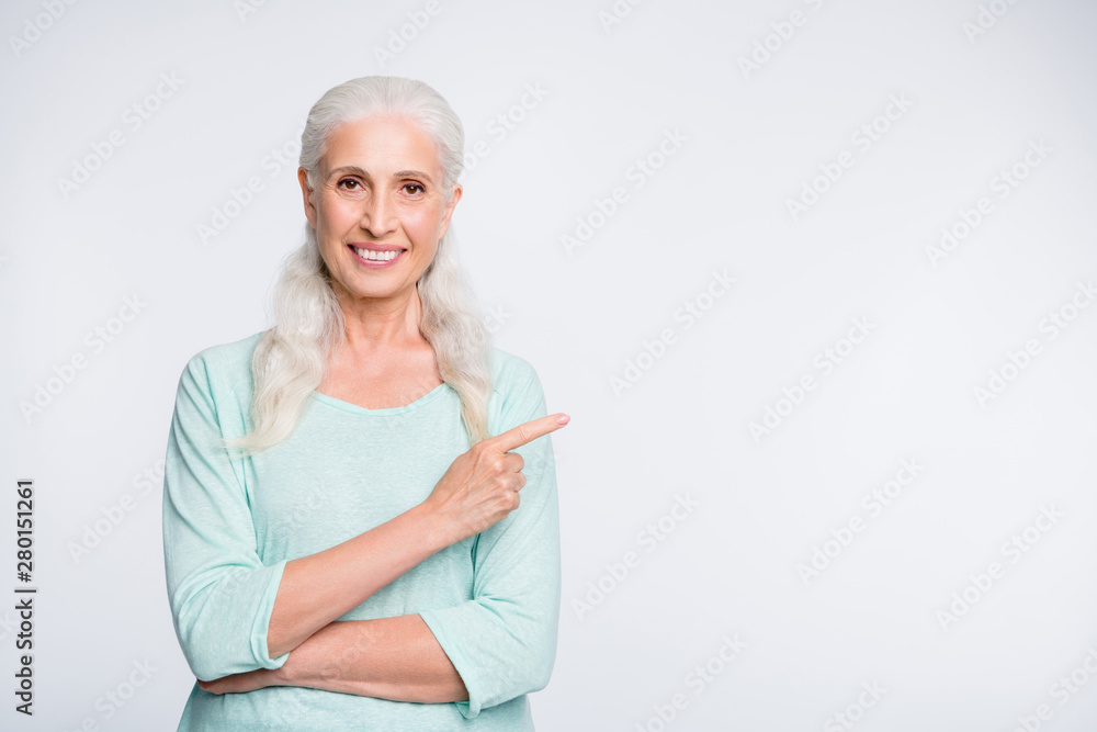 Portrait of charming old woman pointing at copy space showing ads promo wearing teal jumper isolated over white background Portrait of charming old woman pointing at copy space showing ads promo wearing teal jumper isolated over white background
