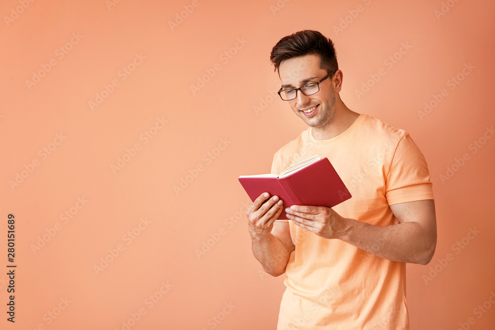 Portrait of handsome man with book on color background