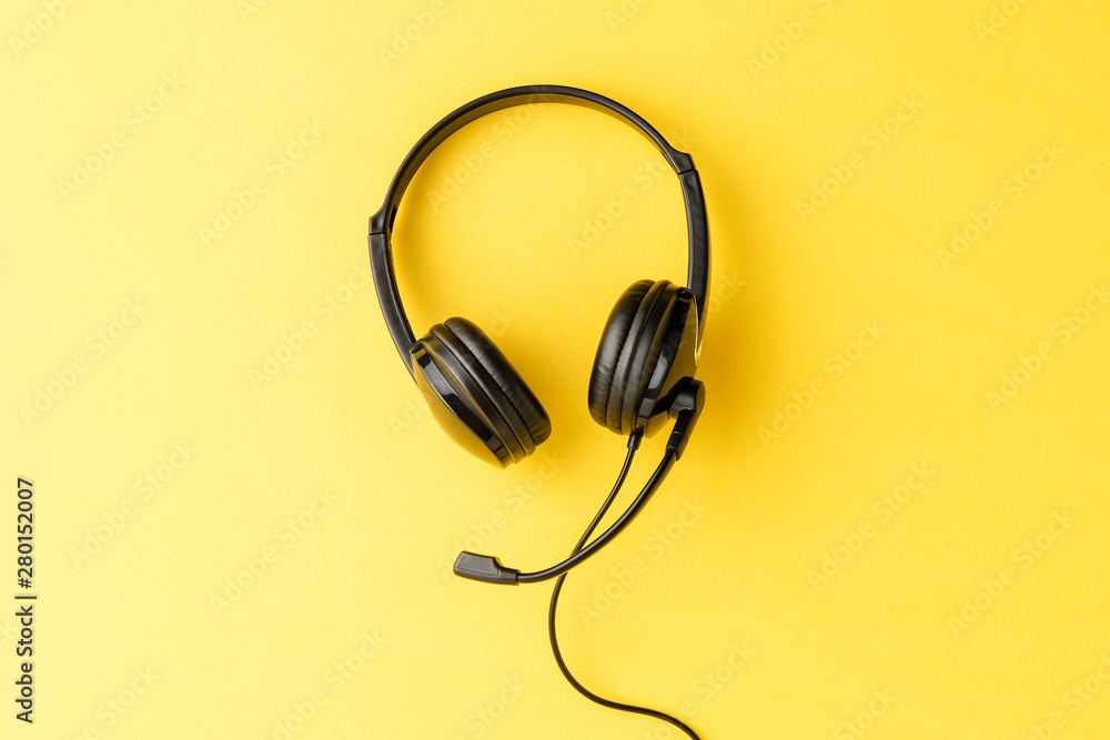 Call center concept with helpdesk headphones on yellow background with copyspace Call center concept with helpdesk headphones on yellow background with copyspace