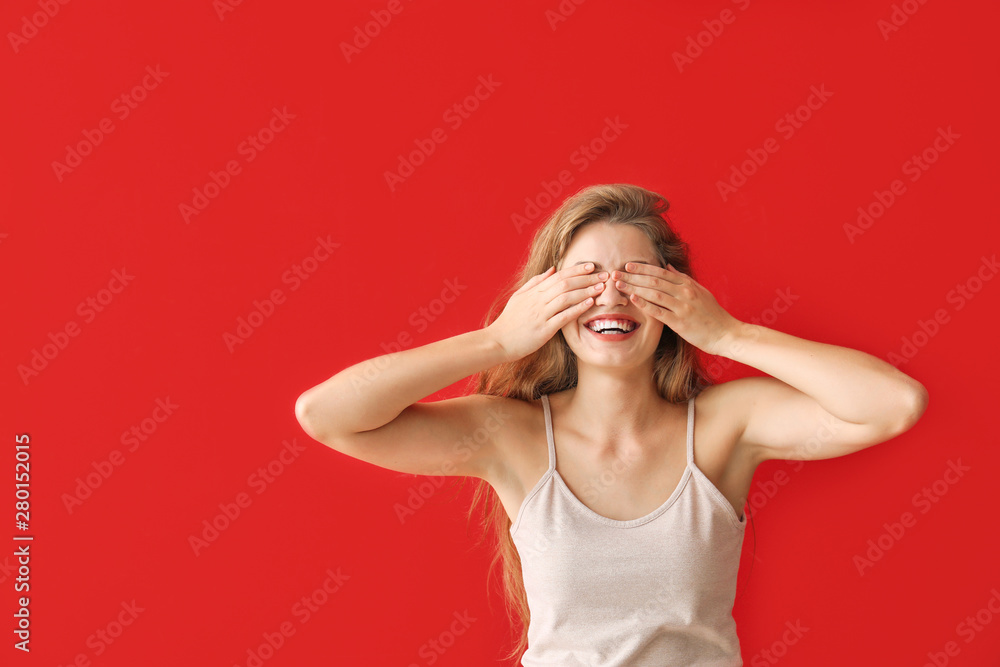 Young woman covering her eyes on color background Young woman covering her eyes on color background