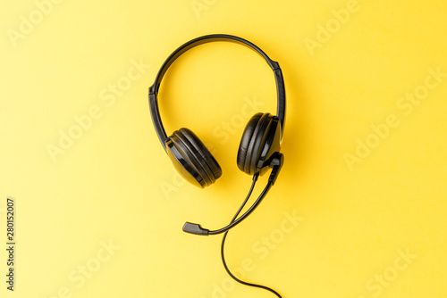 Call center concept with helpdesk headphones on yellow background with copyspace
