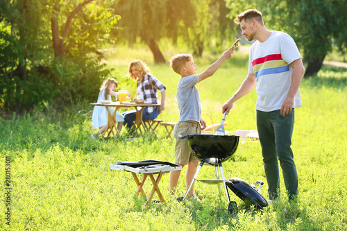 Father with son cooking tasty food on grill outdoors