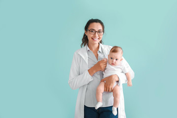 Pediatrician with cute little baby on color background
