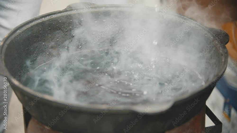 Some water boiling at the bottom of a large cast iron pan Stock 비디오