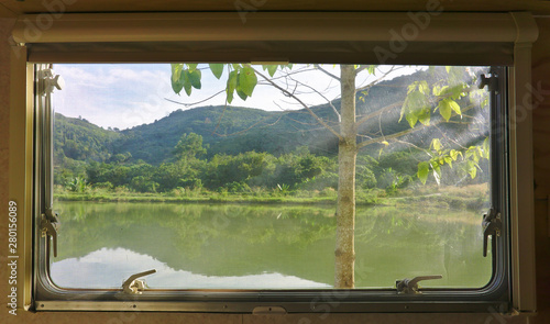 Landscape mountain, forest and lake view outside campervan vehicle window with mosquito net