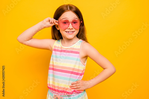 Portrait of cute child touching specs isolated over yellow background
