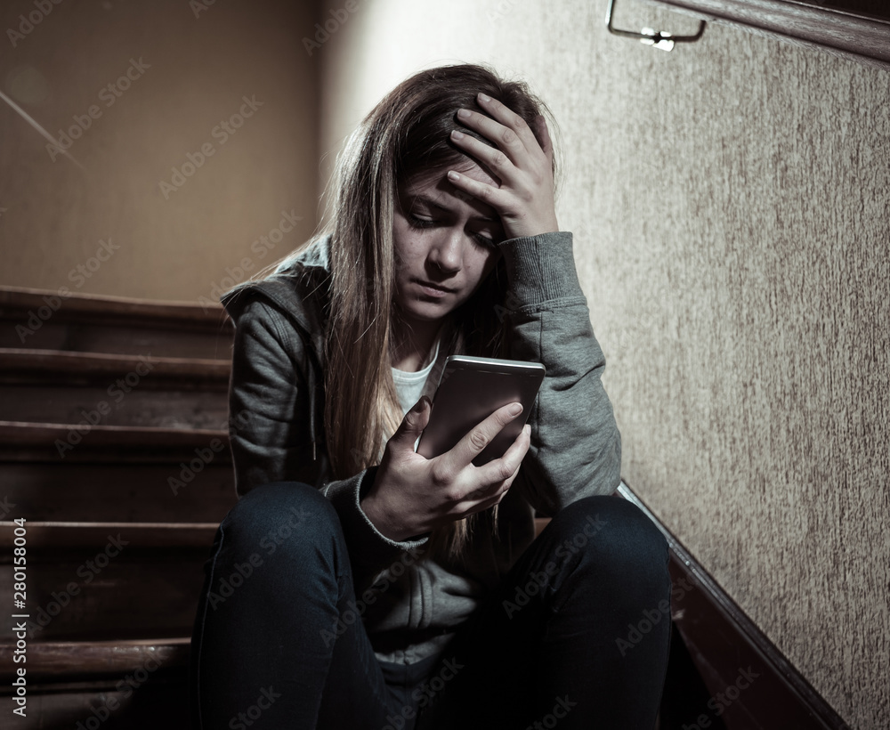 Φωτογραφία Sad depressed unhappy teenager girl suffering from cyberbullying by mobile smart phone sitting alone
