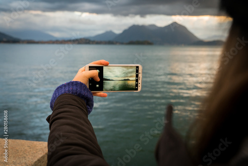 woman with phone taking a picture in a lake 