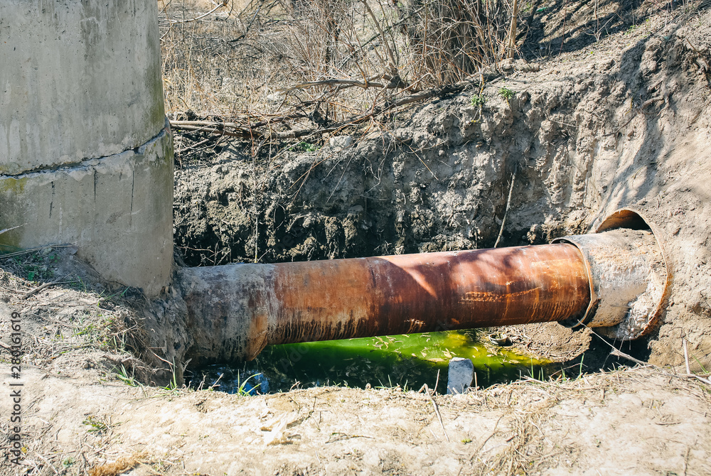 Environment pollution. Old pipe in the field. Green dirty water. Environment pollution. Old pipe in the field. Green dirty water.