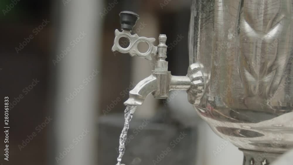 Boiling water running down from a large metal samovar - water stream comes out Boiling water running down from a large metal samovar - water stream comes out