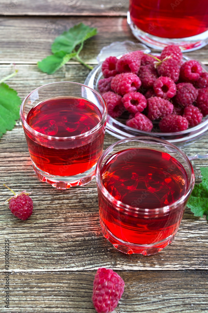 Raspberry liqueur in glass, fresh natural ripe organic berries and green leaves on a rustic wood background. Alcoholic flavored drink. Raspberry liqueur in glass, fresh natural ripe organic berries and green leaves on a rustic wood background. Alcoholic flavored drink.