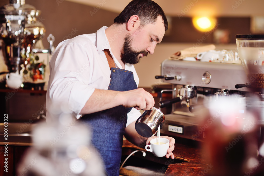 portrait of a handsome bearded barista preparing coffee on the background of a coffee shop and a coffee machine