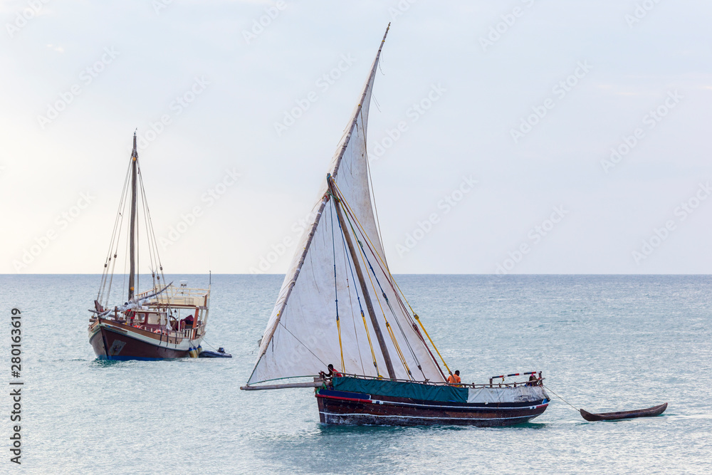 traditional dhow sailing boat alomgside a modern leasure craft