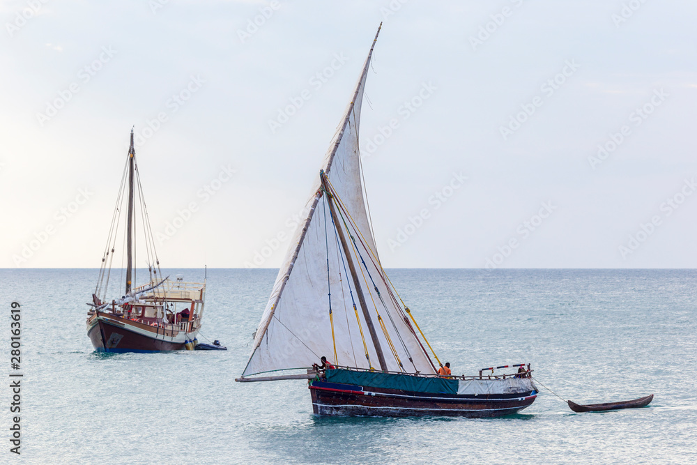 traditional dhow sailing boat alomgside a modern leasure craft traditional dhow sailing boat alomgside a modern leasure craft