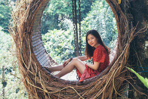 Pretty Asian woman is sitting on straw nest, Ubud, Bali.