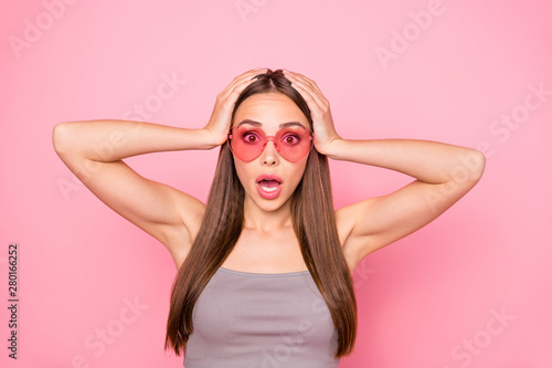 Close up photo of astonished person touching her head shouting wearing gray tank-top isolated over pink background