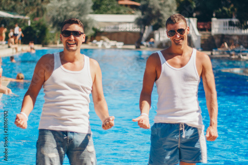 the concept of recreation, tourism - two smiling inflated men with glasses having fun by the pool