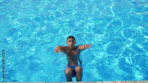 Sportive boy pushing off a swimming pond curb and moving on his back in slo-mo