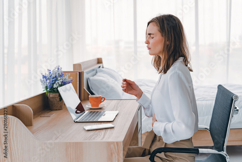 Foto Business woman feeling painful from stomachache illness during working at office, hands touching her stomach and awareness of her Appendicitis sickness