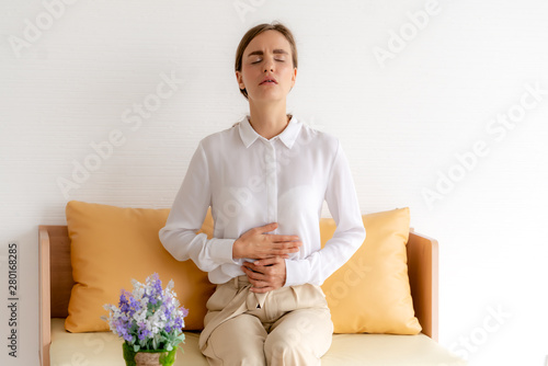 Business woman feeling painful from stomachache illness during working at office, hands touching her stomach and awareness of her Appendicitis sickness. Health insurance care. Insurance concept
