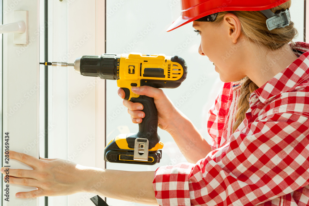 Woman using drill on window Woman using drill on window