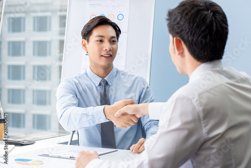 Young Asian businessman making handshake with partner