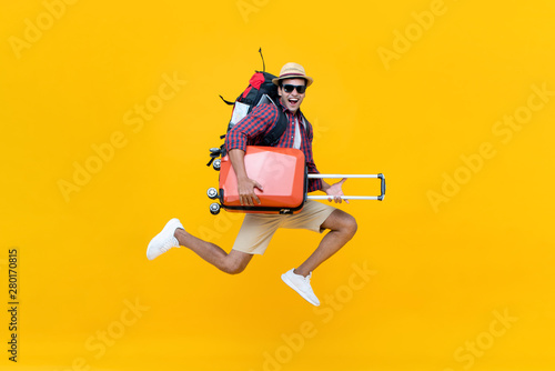 Excited happy young Asian man tourist with luggage jumping