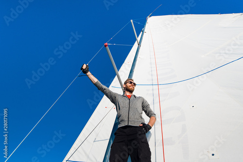 Low angle view of sailor operating windlass on yacht. Working with ropes and sail