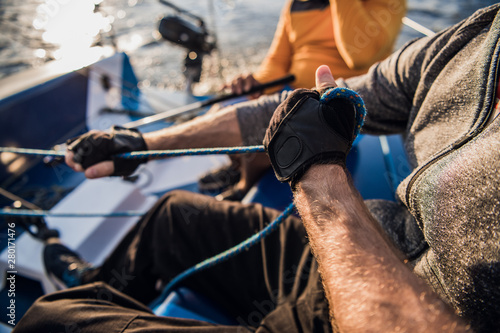 Man's hand with boat rope. Yachtsman moors his motor boat at jetty. Close up hands and bow of the boat. © romankosolapov