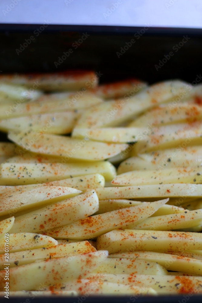 Potato slices drizzled with olive oil, basil and smoked paprika, ready for oven. Selective focus. Potato slices drizzled with olive oil, basil and smoked paprika, ready for oven. Selective focus.