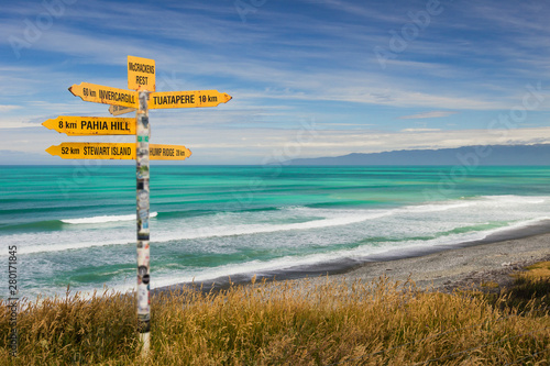 Distance and direction signpost on a beautiful, sunny beach. McCracken's Rest, Southland, New Zealand.