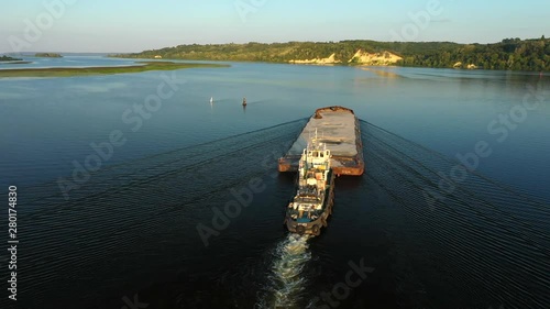 Aerial video river pusher boat transporting barge with dry cargo in middle of summer river, Central Europe