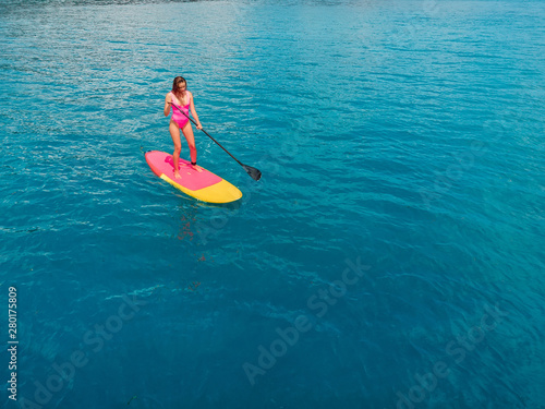 Aerial view of woman on stand up paddle board in blue ocean. © artifirsov