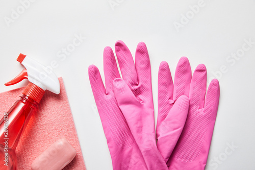 top view of pink rag and soap, rubber gloves and spray