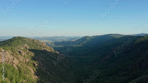 The panoarama shot of the area. View over the dense forest between the mountain ranges. In the background is a mountain range. Evening sky. photo