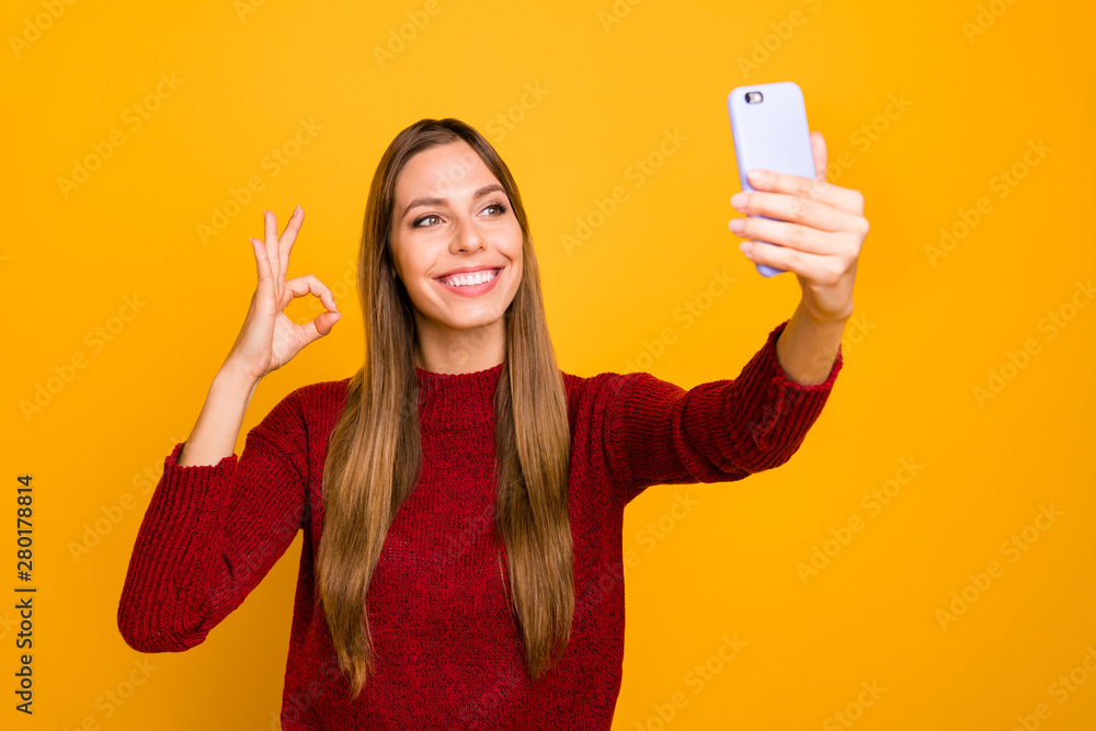 Pretty lady holding telephone hands making selfies showing okey symbol wear knitted pullover isolated yellow background Pretty lady holding telephone hands making selfies showing okey symbol wear knitted pullover isolated yellow background